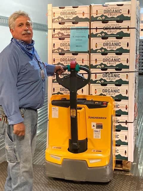 Un empleado con un palé lleno de melocotones frescos de Colorado 