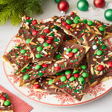 A festive plate of chocolate-covered treats topped with red and green candies and colorful sprinkles.