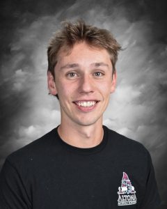 Smiling person in a black Altona Middle School shirt against a cloudy backdrop.